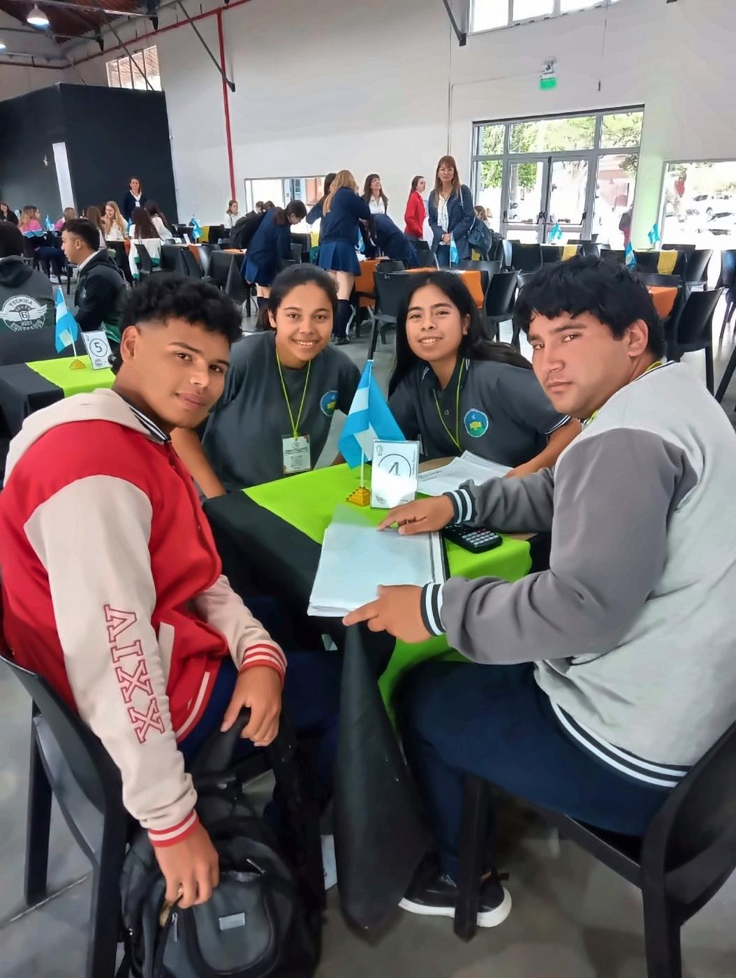 Equipo de estudiantes sonriendo en su mesa durante una ronda de decisiones