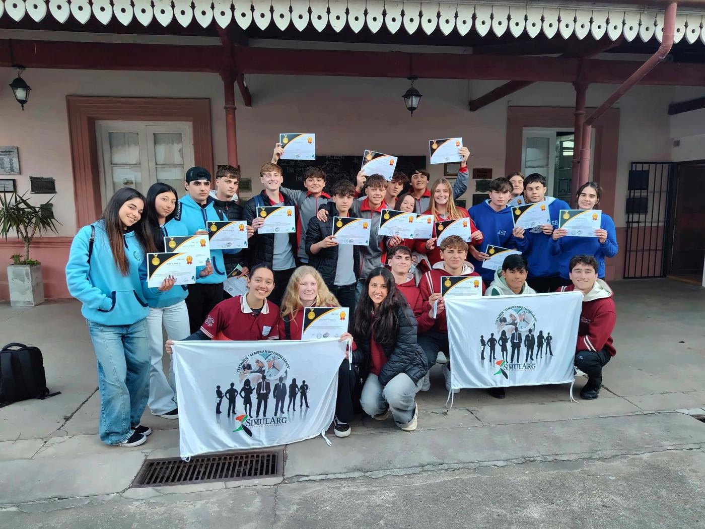Estudiantes de distintas escuelas con sus diplomas y las banderas del certamen