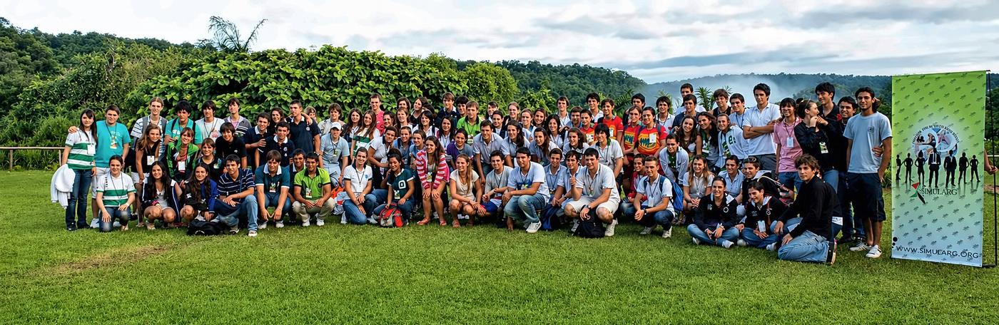 Foto grupal de las delegaciones al aire libre, con la selva misionera y la bruma de las cataratas al fondo