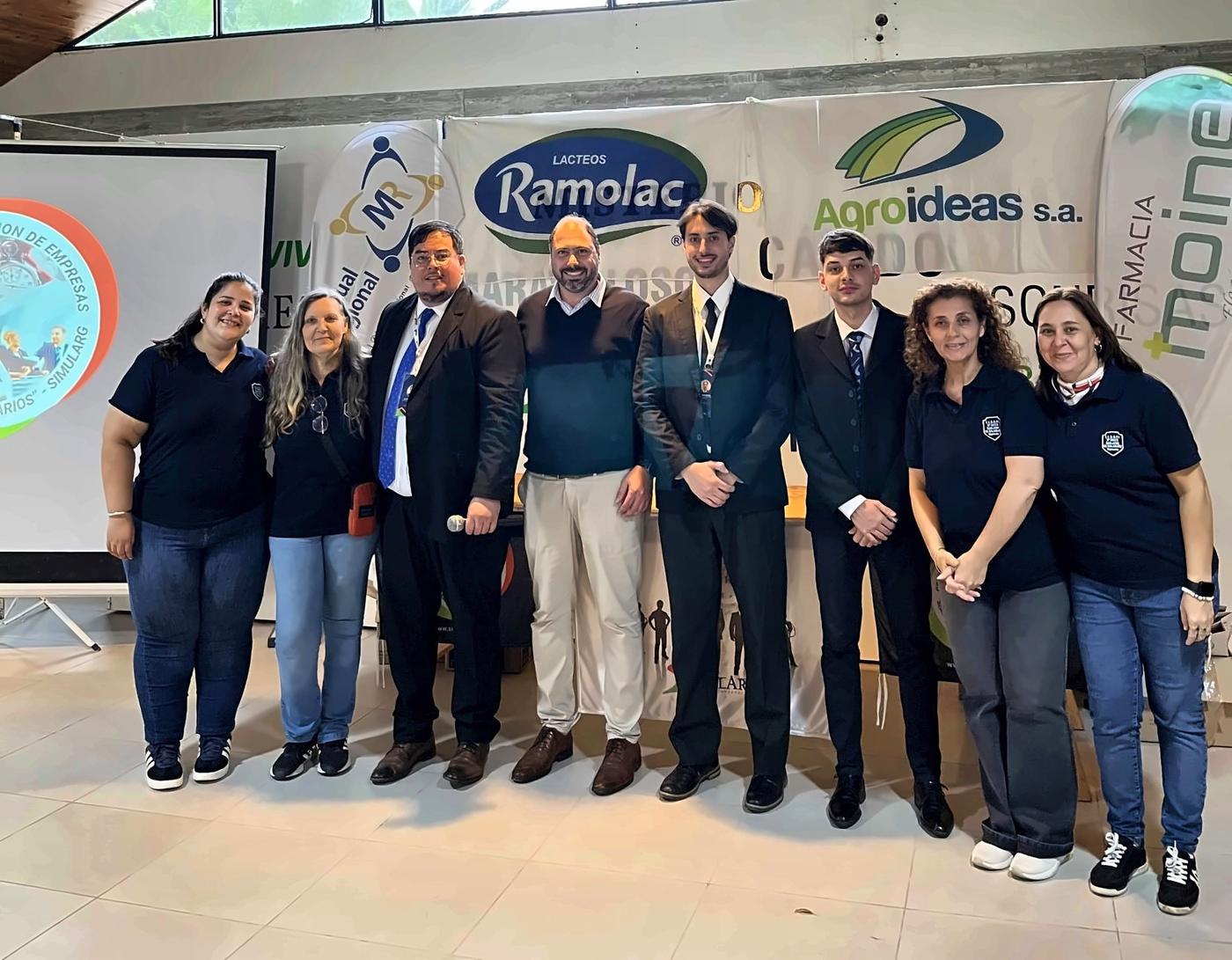 Docentes organizadores y equipo de coordinación en una sede regional, junto a los banners de las empresas que acompañan