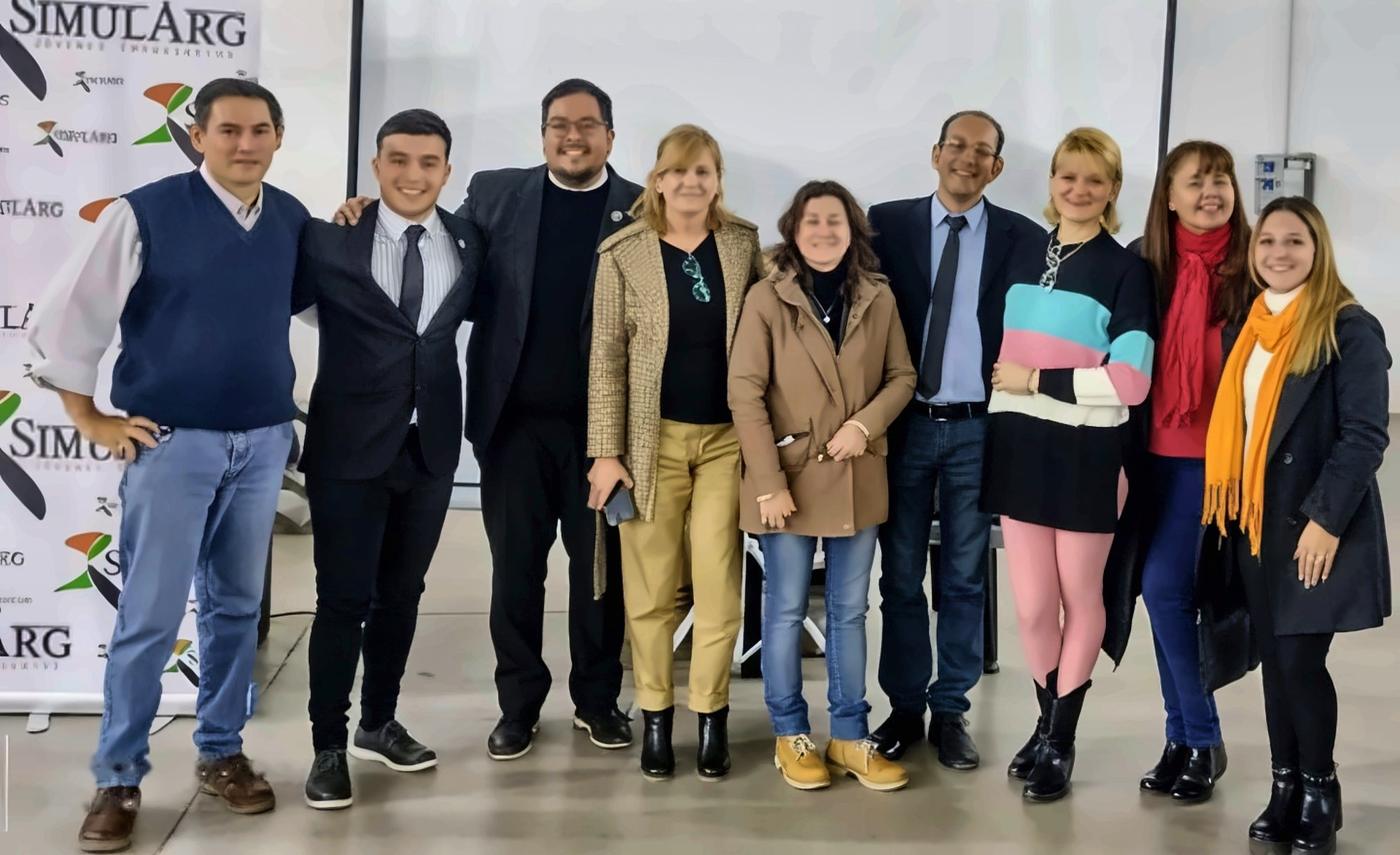 Docentes organizadores y equipo de SimulArg en una sede regional, frente al banner del certamen